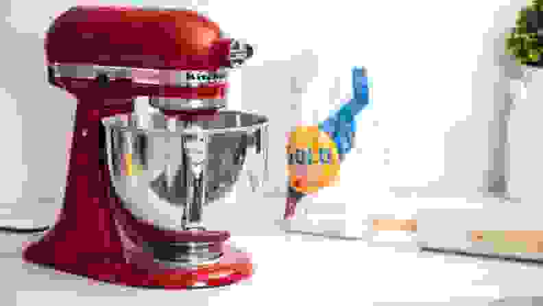 A red KitchedAid stand mixer sits on a countertop next to flour and rolling pin.