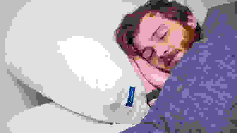 A man sleeps on the Casper Original Pillow under a blue blanket