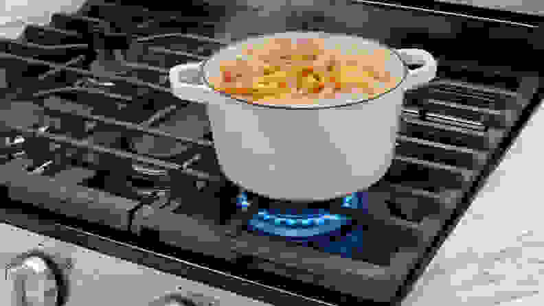 Some pasta being prepared on a pot on the oven top.