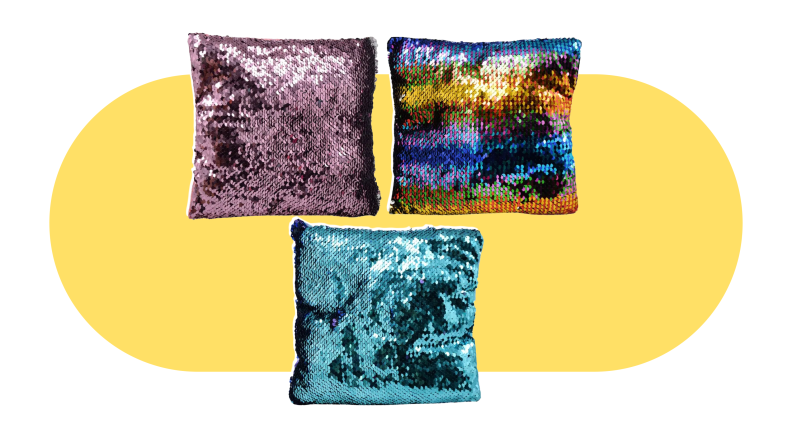 Three rainbow colored sequin pillows on a yellow background.