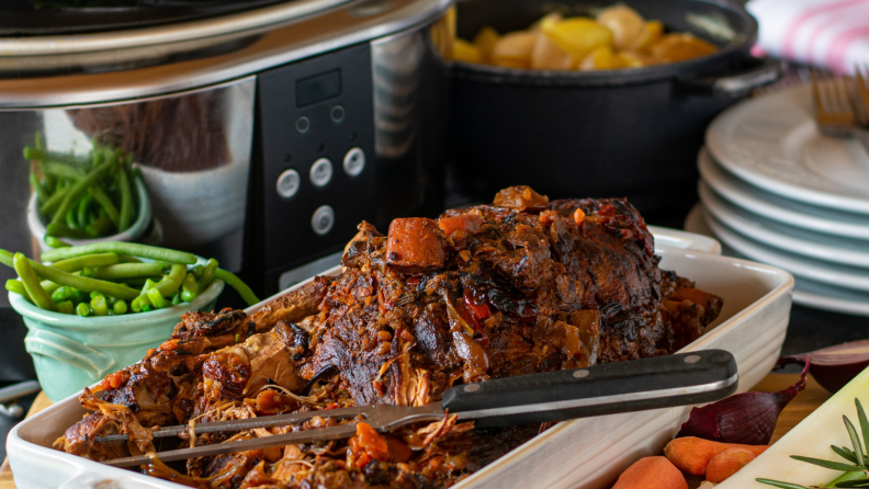 Old-fashioned pot roast in dish next to crock pot.