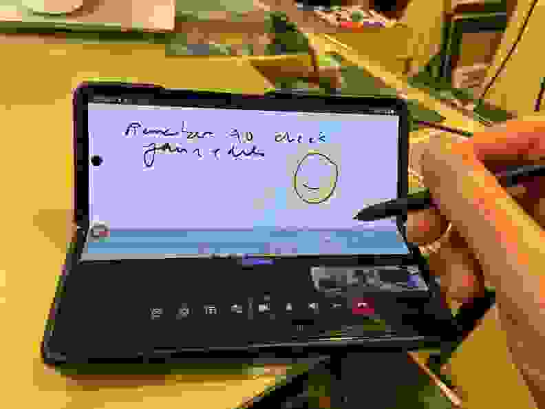 Person using stylus pen to write on screen of smartphone.