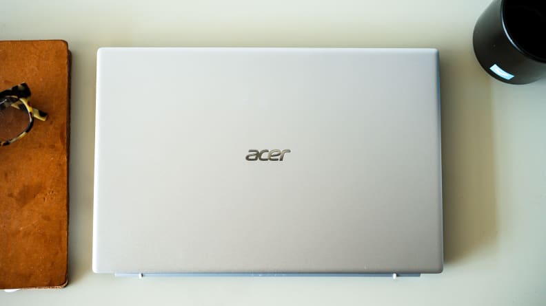 A closed silver laptop on top of a white desk with various objects on either side of it.