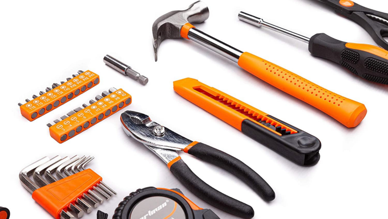Household tools including a hammer, pliers, and a wrench are arranged on a surface.