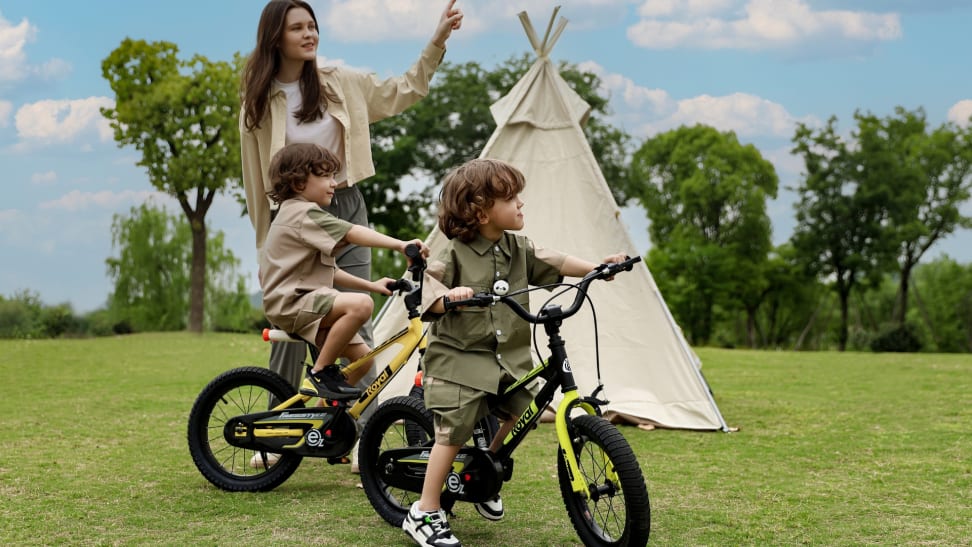 2 children on RoyalBaby's EZ bikes play with their mom near a tent