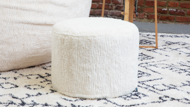 A close-up of Lovesac’s white furry ottoman.