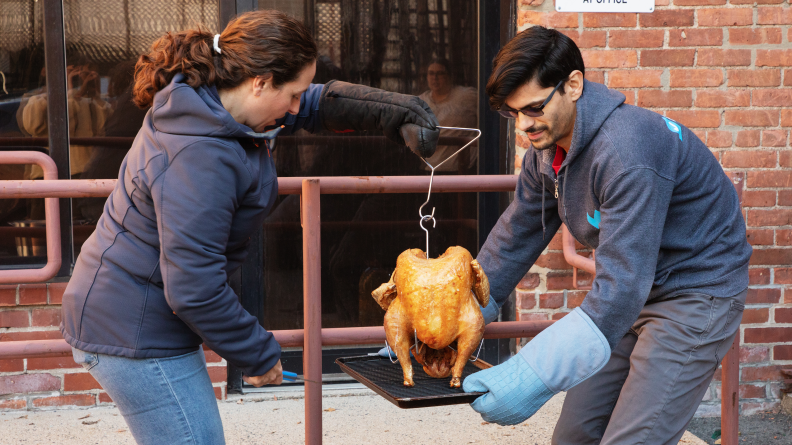 Two people handling a fried turkey outdoors