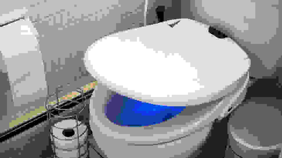 A bidet attachment on a toilet. The bowl glows mysteriously blue.