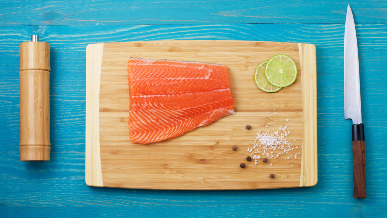 A bamboo cutting board with a slice of salmon.