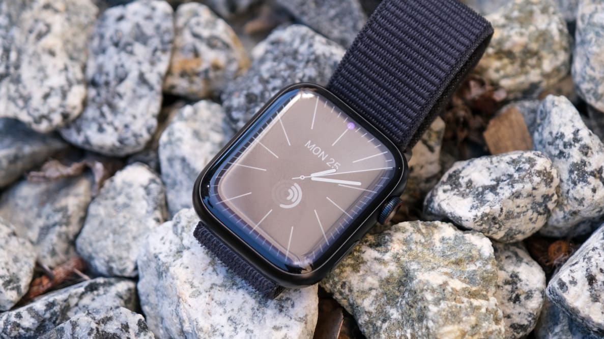 An Apple Watch Series 9, with a blue band, sits on a bed of rocks