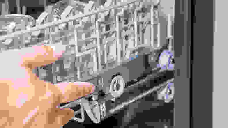 A hand reaches into frame to adjust the height of the upper rack.