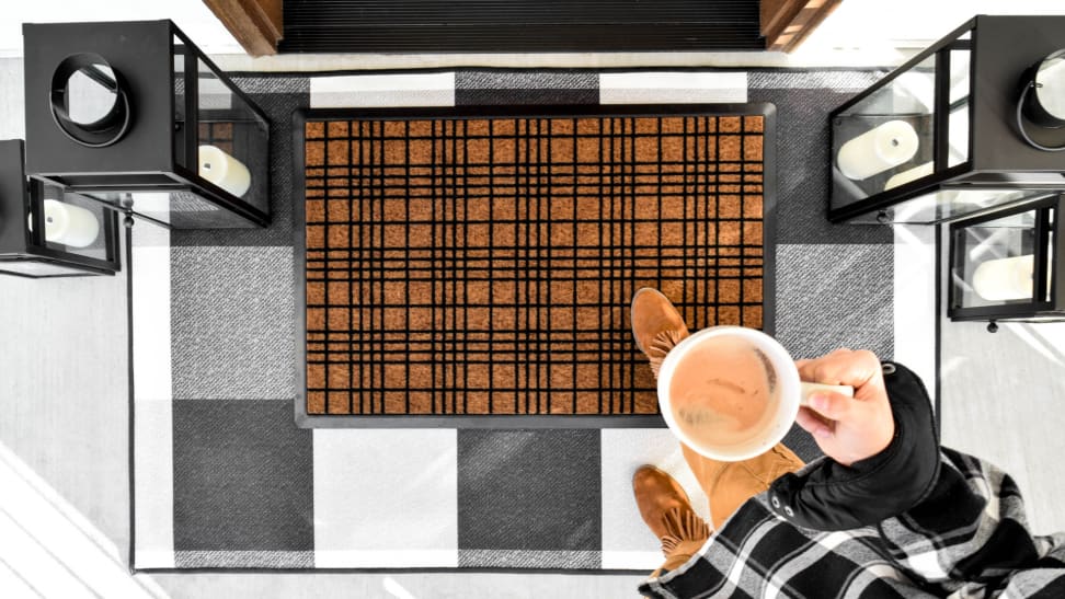 A person enters their home while stepping on a Ruggable welcome mat.