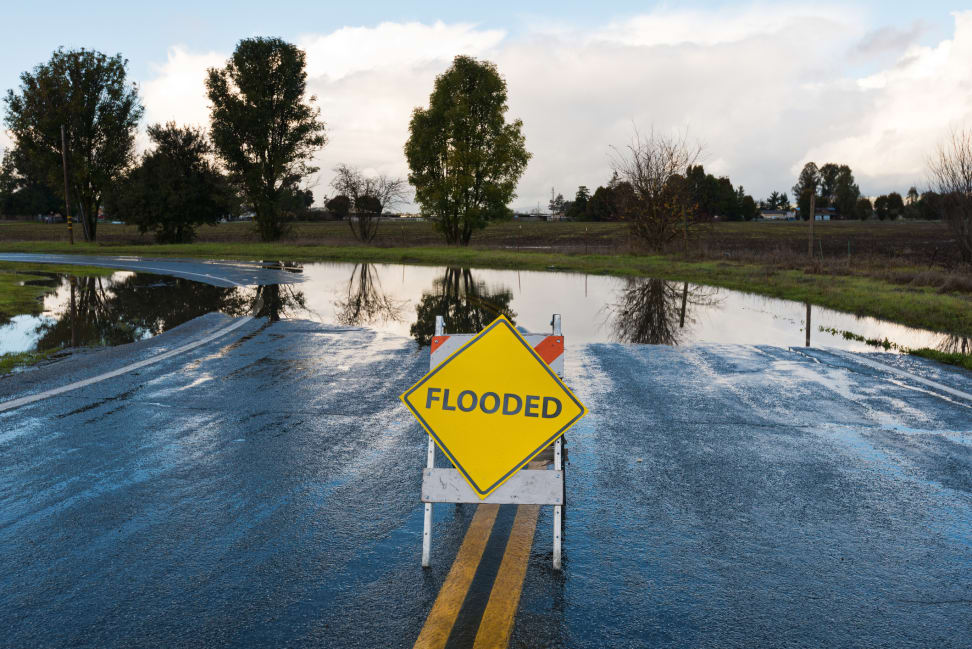 A flooded sign appears in the middle of the road, stopping traffic from entering a large flooded area