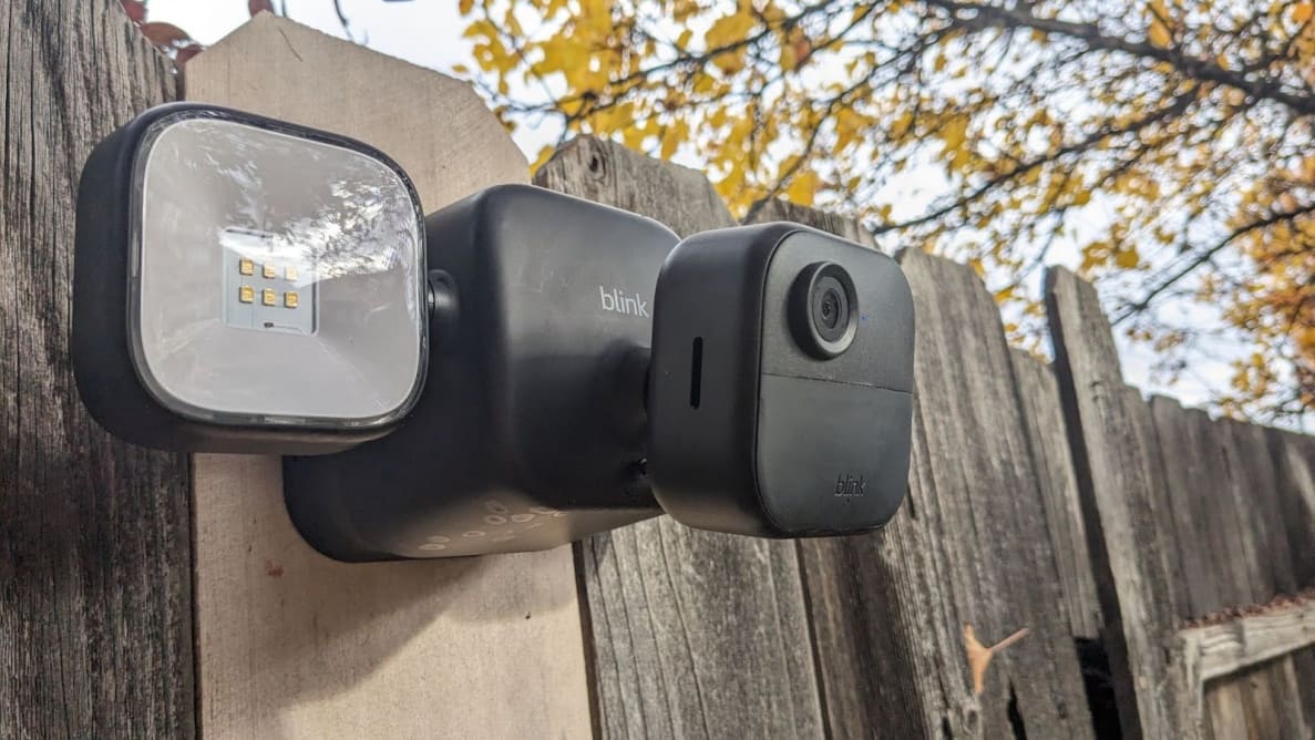Side view of the Blink Outdoor 4 Floodlight Camera mounted on wooden fence outdoors.