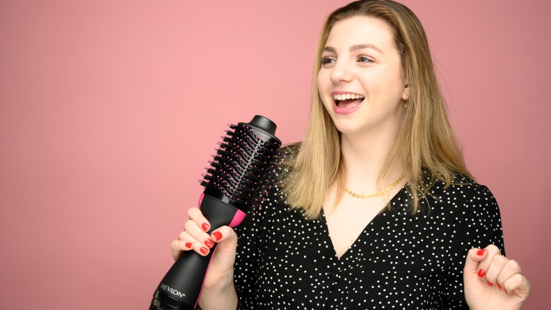 A woman holding a Revlon One-Step Hair Brush, among the best 30th birthday gift ideas.
