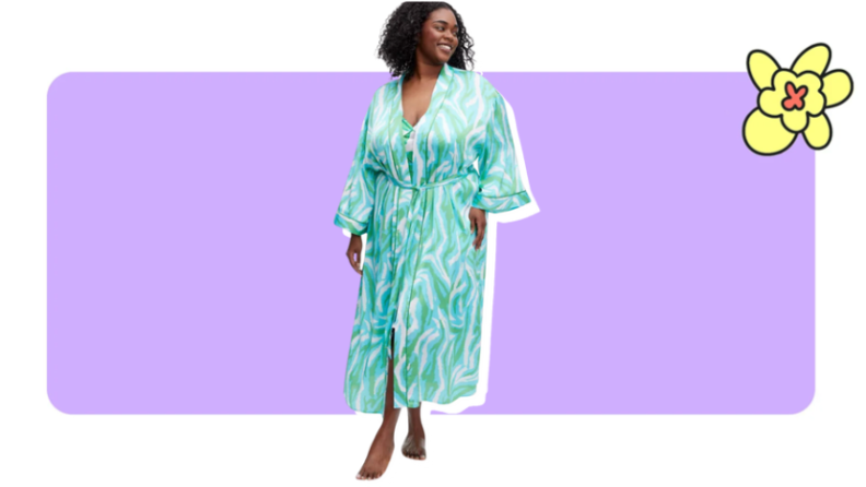 Model showcasing a satin, blue, white and green zebra printed Diane Von Furstenberg robe in front of purple background with a yellow cartoon flower in the corner.