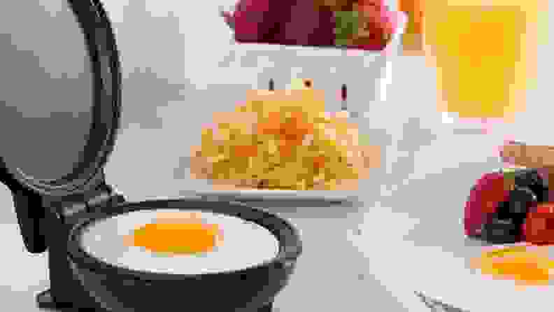 A single egg cooks on the Dash Mini Griddle, surrounded by other cooked eggs plated and ready to eat.