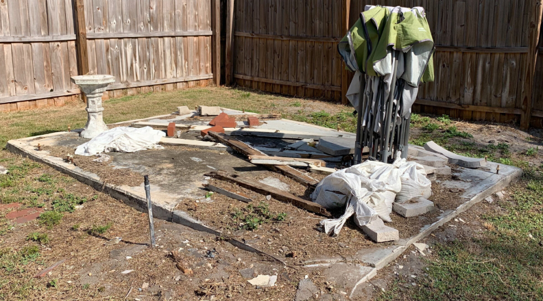 A backyard concrete slab is covered in debris