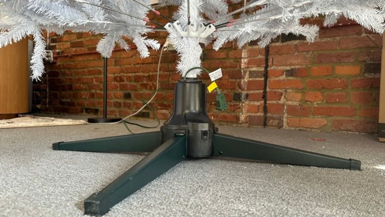 A rotating tree stand for artificial Christmas trees with a white artificial tree attached.