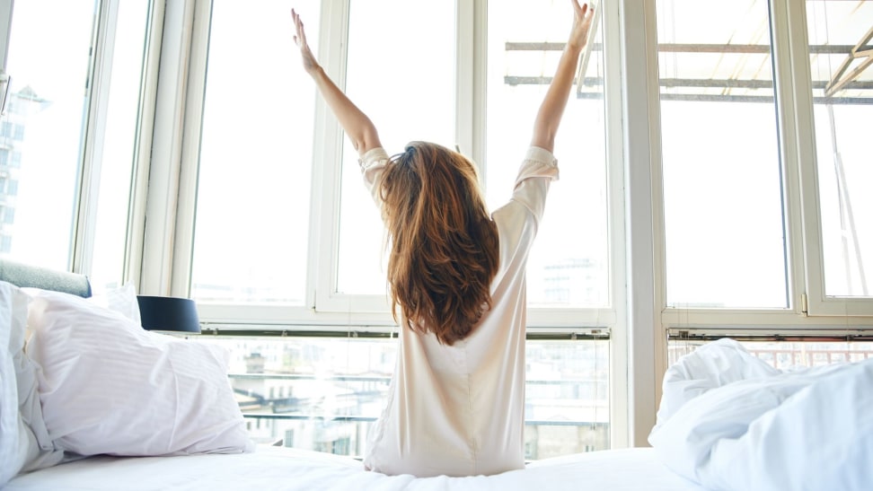 A woman stretches in bed after waking up