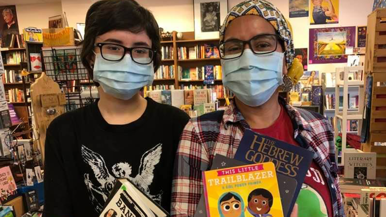 Two people wearing masks inside a bookstore