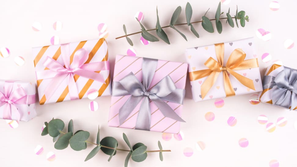 An assortment of colorfully packaged wedding presents surrounded by eucalyptus sprigs.