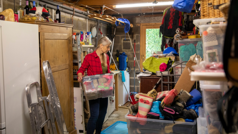 Person using storage bins to organize messy garage.