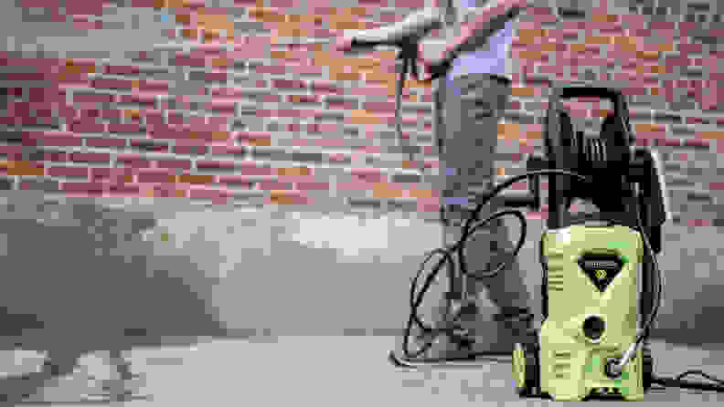 A person sprays a brick wall with the green Wholesun pressure washer.