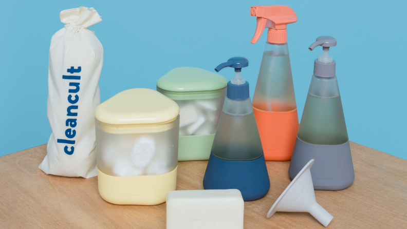 Product shot of multi-colored Cleancult cleaning products on table in front of blue background.