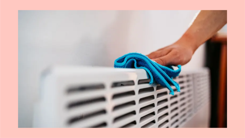 A person wipes a radiator with a cloth.