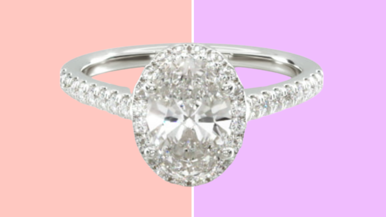 A silver colored ring with an oval center diamond with a halo of paved diamond and small diamond accents on the band.