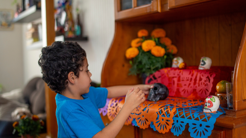 Small child sets up an alter at home, adorning it with skulls.