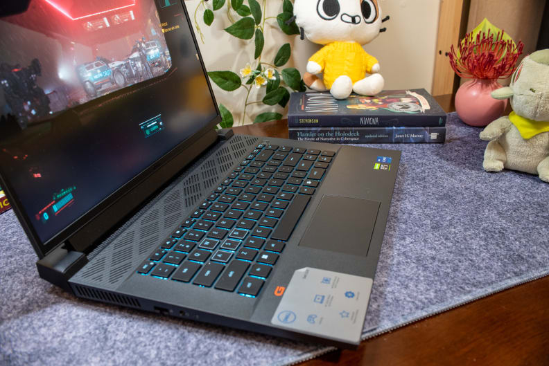 A three-quarter view of an open and powered on black laptop with a blue-lighted keyboard.