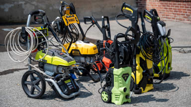 A collection of six pressure washers in a parking lot.