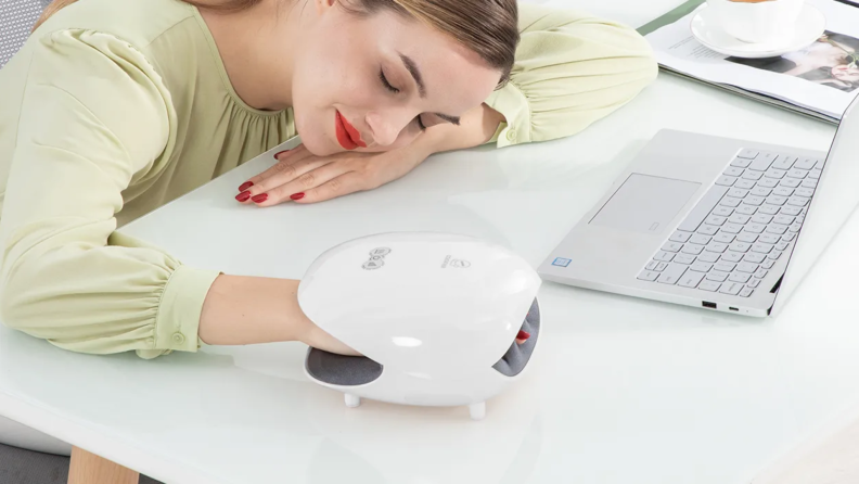 A model rests her head, eyes closed, while enjoying a hand massage with the use of a Comfier hand massager.