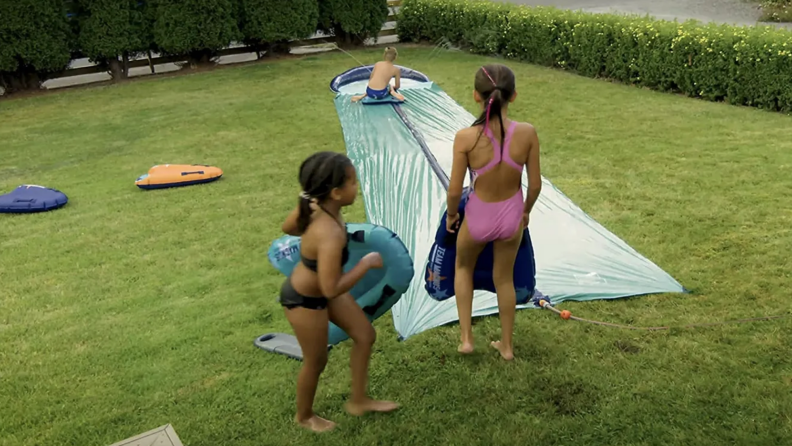 Kids stand by a slip and slide