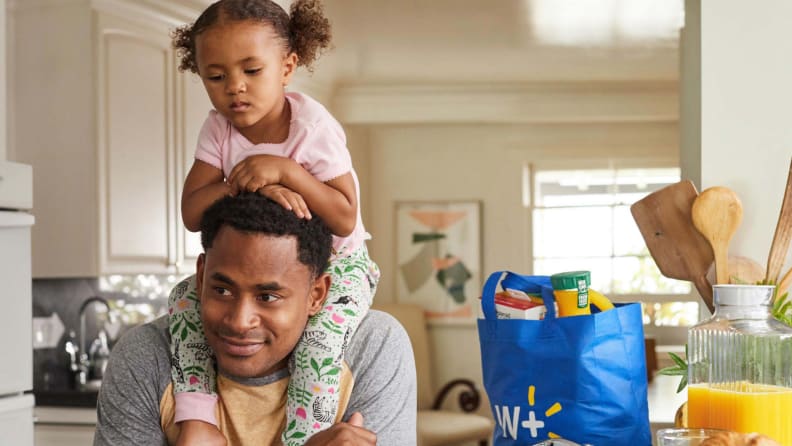 Man with child on shoulders with groceries on counter behind them