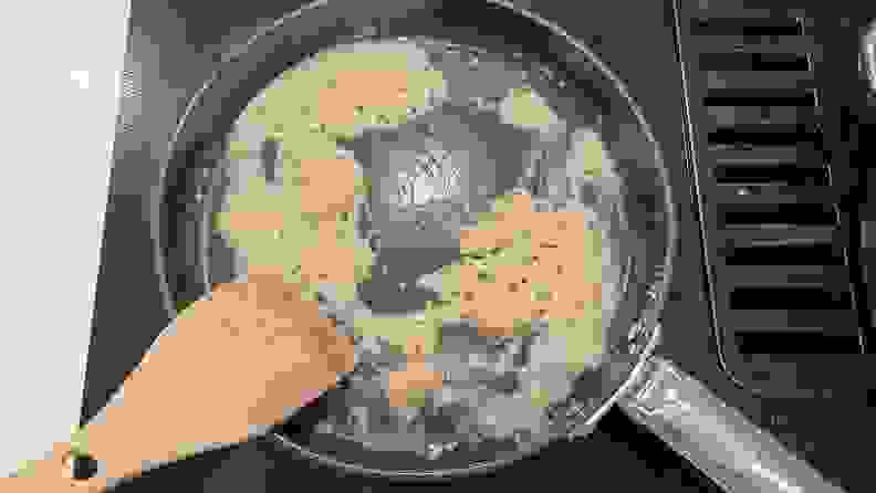 A wooden spoon in a Joseph Joseph cooking pan that is being cleaned.