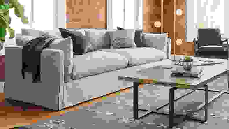 A grey, fluffy couch sits in a modern living room in front of a coffee table.