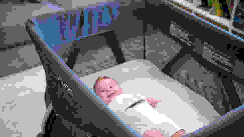 A baby laying in a playard and smiling