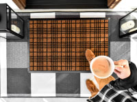 A person enters their home while stepping on a Ruggable welcome mat.