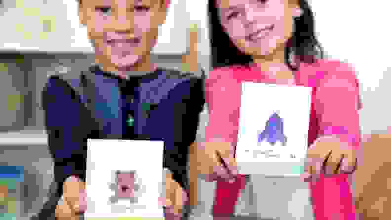 Two children hold holiday cards.