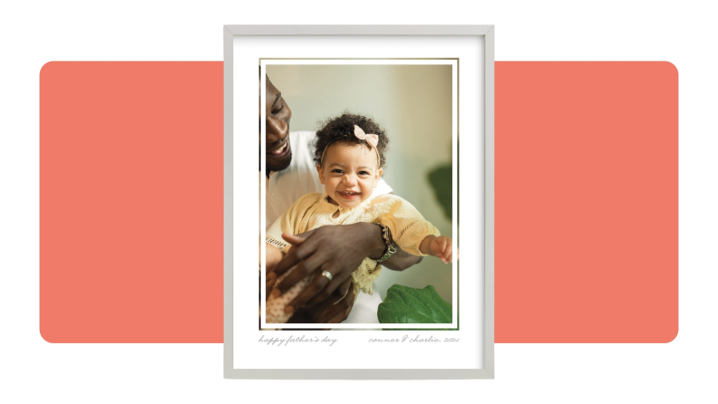 A photo of a small smiling child while parent holds them inside of custom Minted photo frame.