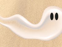 A swipe of suncreen lotion that looks like a ghost with back eyes over a sandy background