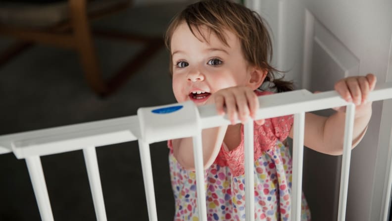 A young child looks over a babygate