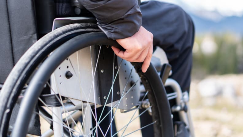 Person holding wheels on wheelchair outdoors