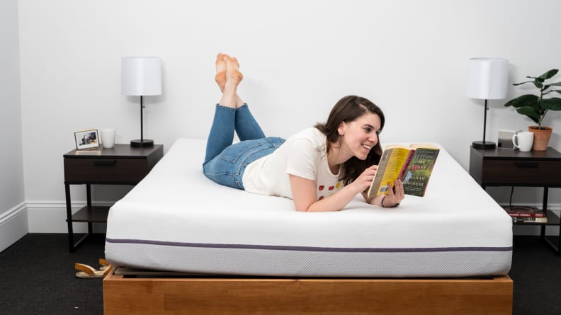 a person lies on their stomach reading on the purple mattress