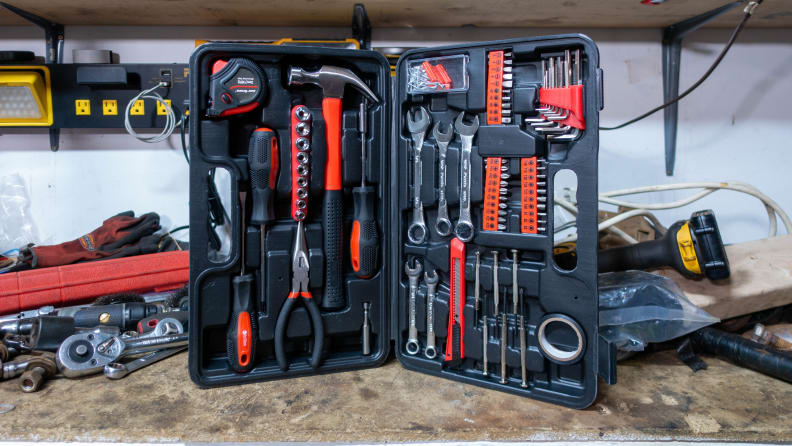 The toolkit standing up in the corner of a work table, surrounded by other tools. The case is splayed open and showcasing all the tools inside.