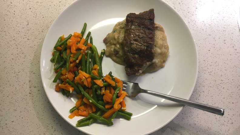 A Reviewed photo of Freshly steak peppercorn with a side of green beans on a white plate.