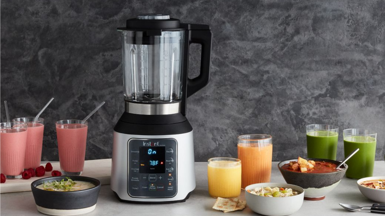 An image of an Instant blender seated on a countertop surrounded by smoothies in glass cups and fruit.